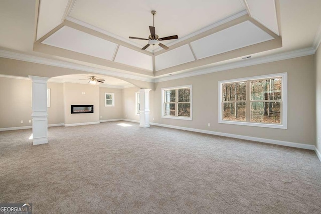 unfurnished living room with arched walkways, a glass covered fireplace, crown molding, and decorative columns