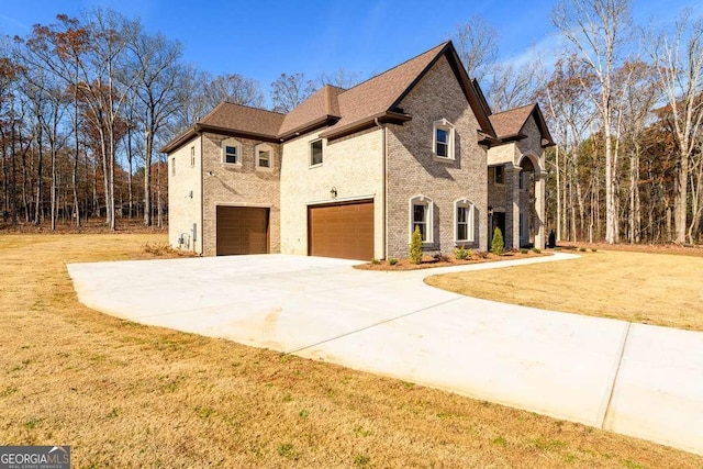 view of front of home with concrete driveway, a garage, brick siding, and a front yard