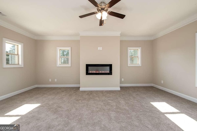 unfurnished living room with a glass covered fireplace, crown molding, plenty of natural light, and carpet floors