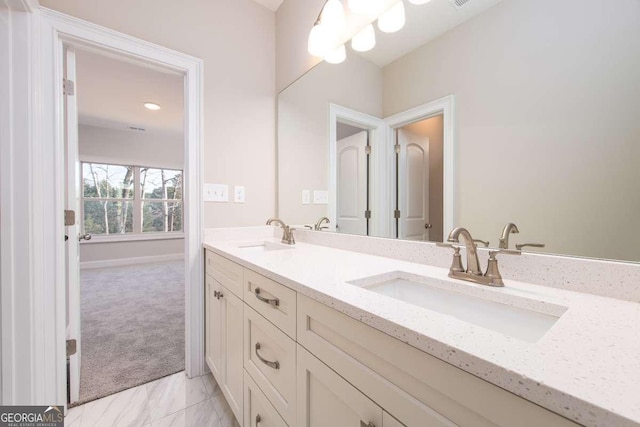 bathroom with double vanity, baseboards, a sink, and marble finish floor