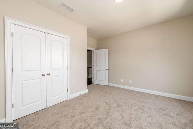 unfurnished bedroom featuring carpet, visible vents, a closet, and baseboards