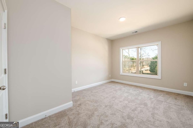 carpeted spare room featuring baseboards and visible vents