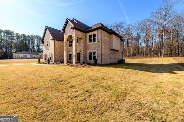 view of side of property featuring brick siding, central air condition unit, and a yard