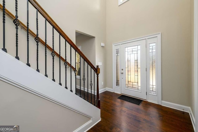 entrance foyer with baseboards, stairs, wood finished floors, and a towering ceiling