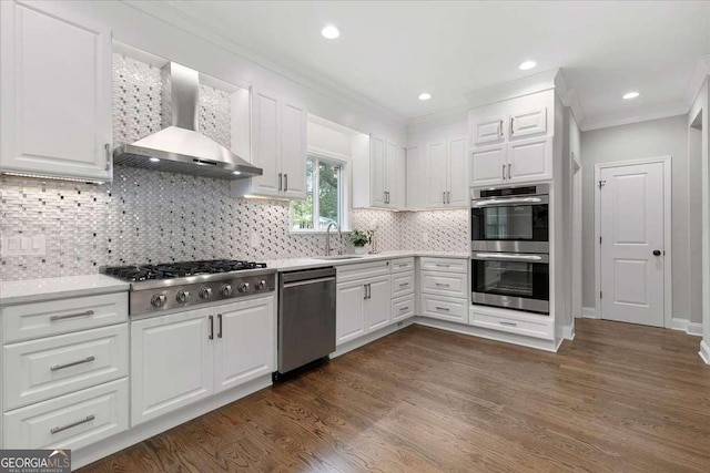 kitchen featuring wall chimney range hood, decorative backsplash, appliances with stainless steel finishes, dark hardwood / wood-style flooring, and white cabinetry