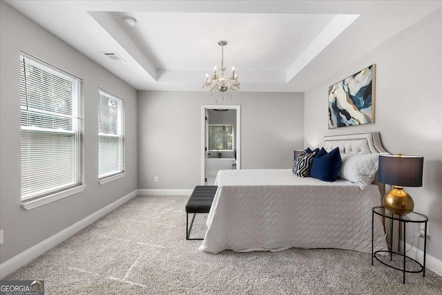 bedroom featuring ensuite bathroom, a raised ceiling, light colored carpet, and an inviting chandelier