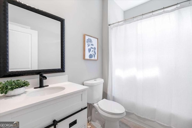 bathroom with walk in shower, vanity, and toilet