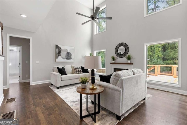 living room featuring ceiling fan, dark hardwood / wood-style flooring, and a towering ceiling