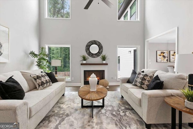 living room with hardwood / wood-style flooring, ceiling fan, and a high ceiling