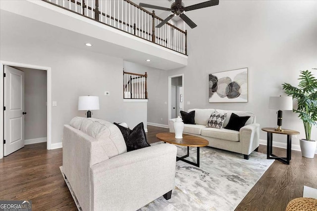 living room featuring a towering ceiling, ceiling fan, and dark wood-type flooring