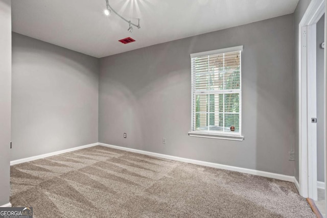 empty room with carpet floors, rail lighting, and a wealth of natural light