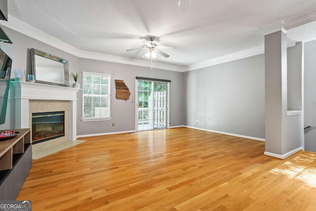 unfurnished living room featuring ceiling fan, light wood-type flooring, a textured ceiling, a premium fireplace, and ornamental molding