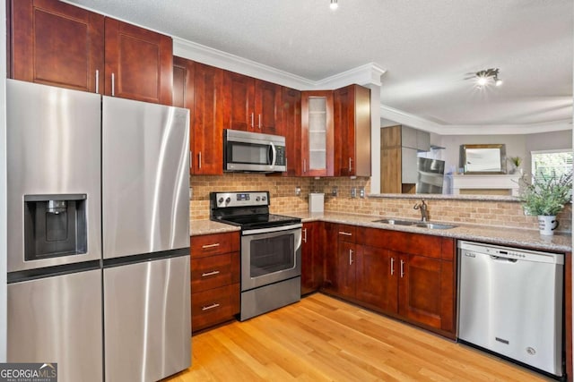 kitchen with light stone countertops, light wood-type flooring, tasteful backsplash, stainless steel appliances, and sink