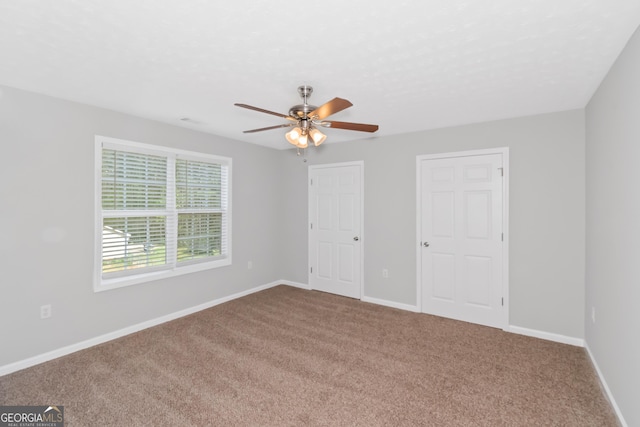 unfurnished bedroom with carpet, ceiling fan, and multiple closets