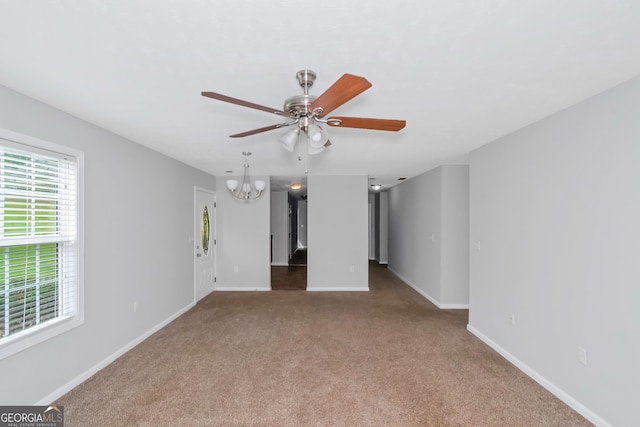 carpeted spare room with ceiling fan with notable chandelier