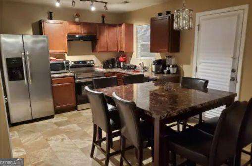 kitchen featuring a breakfast bar, pendant lighting, dark stone countertops, and stainless steel appliances