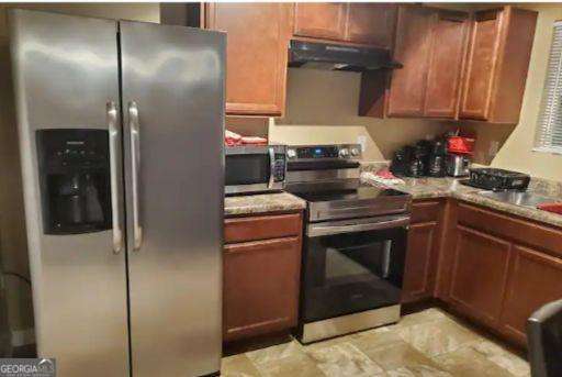 kitchen featuring light stone counters, stainless steel appliances, and extractor fan