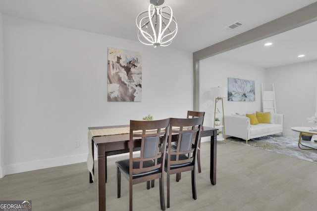 dining area with beamed ceiling, light wood-type flooring, and a notable chandelier