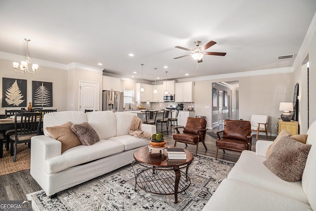 living room featuring dark hardwood / wood-style floors, crown molding, and ceiling fan with notable chandelier