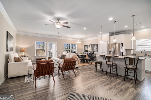 living room featuring dark hardwood / wood-style flooring, ceiling fan with notable chandelier, and ornamental molding