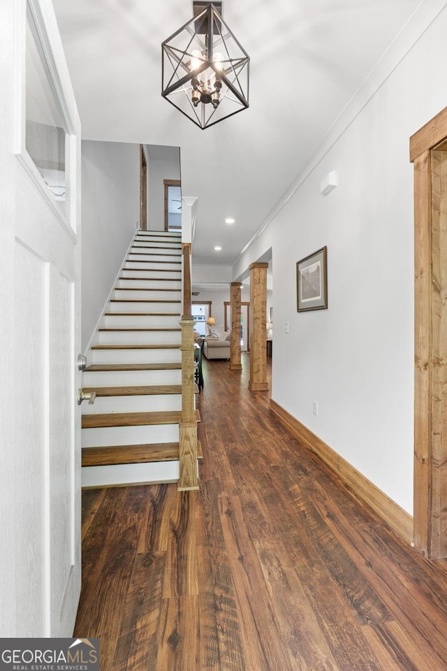 stairway featuring an inviting chandelier, wood-type flooring, and ornamental molding