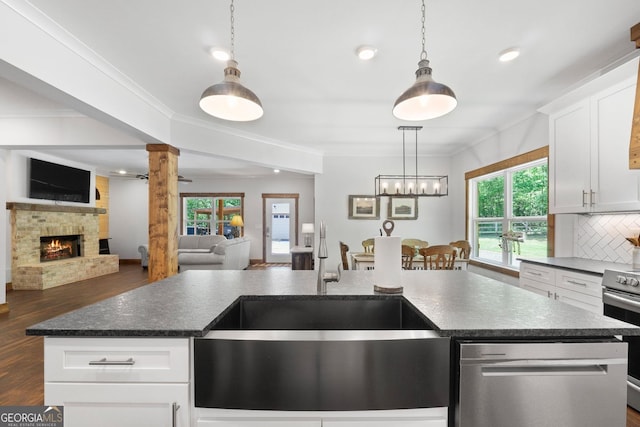 kitchen featuring a center island with sink, white cabinetry, and decorative columns