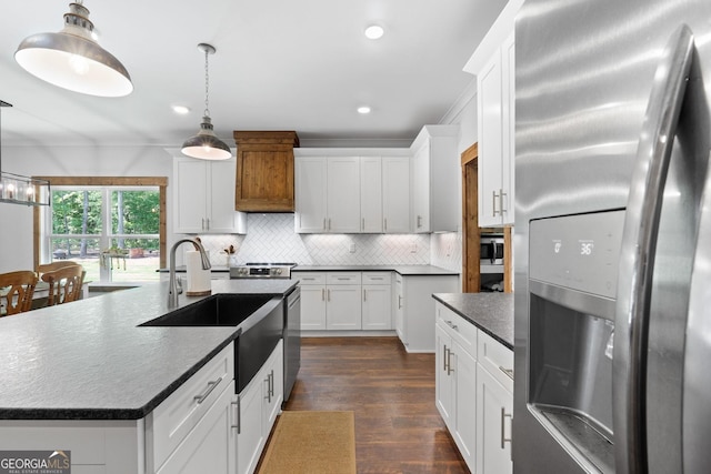 kitchen with a center island with sink, white cabinets, sink, hanging light fixtures, and stainless steel appliances