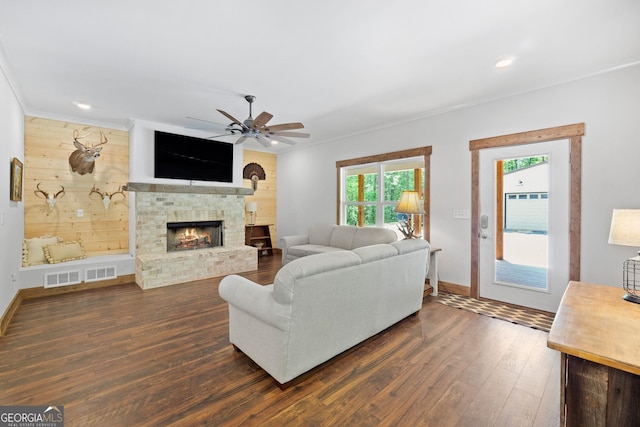 living room with plenty of natural light, ceiling fan, a stone fireplace, and dark hardwood / wood-style floors