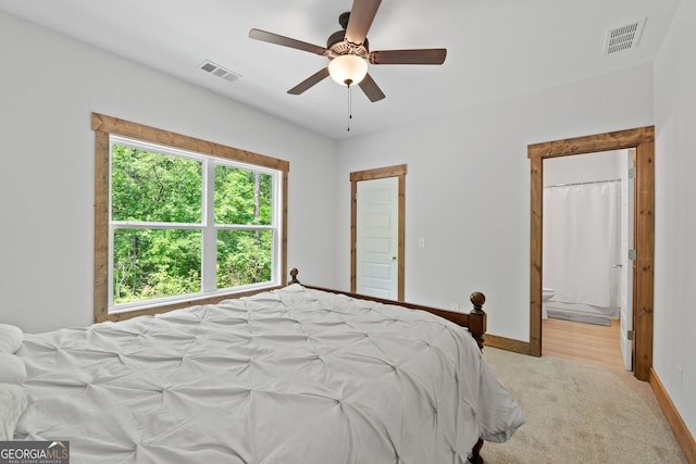 carpeted bedroom with ensuite bath and ceiling fan