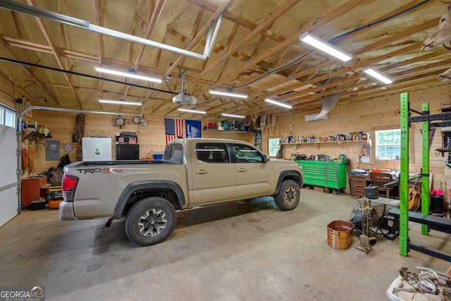 garage featuring wooden walls, electric panel, and a garage door opener