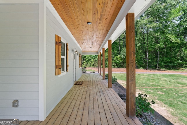 wooden deck featuring covered porch and a yard