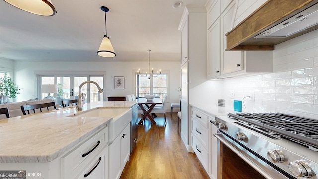 kitchen featuring white cabinetry, stainless steel appliances, backsplash, a kitchen island with sink, and custom range hood