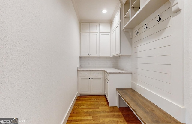 mudroom with ornamental molding and light wood-type flooring