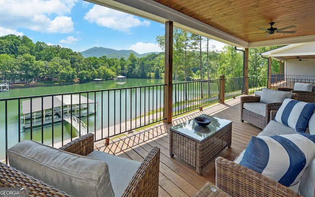 wooden terrace with ceiling fan, a water and mountain view, and an outdoor living space