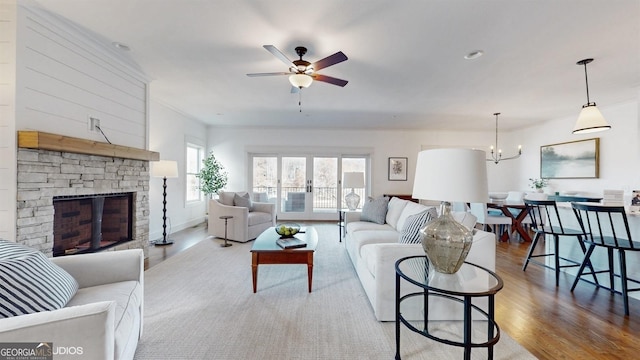 living room with a fireplace, ceiling fan with notable chandelier, and light hardwood / wood-style flooring