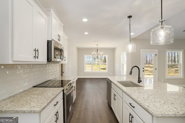 kitchen with stainless steel appliances, white cabinetry, a sink, and an island with sink