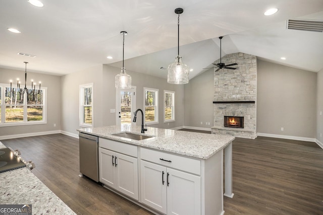 kitchen featuring open floor plan, hanging light fixtures, stainless steel dishwasher, white cabinetry, and a sink