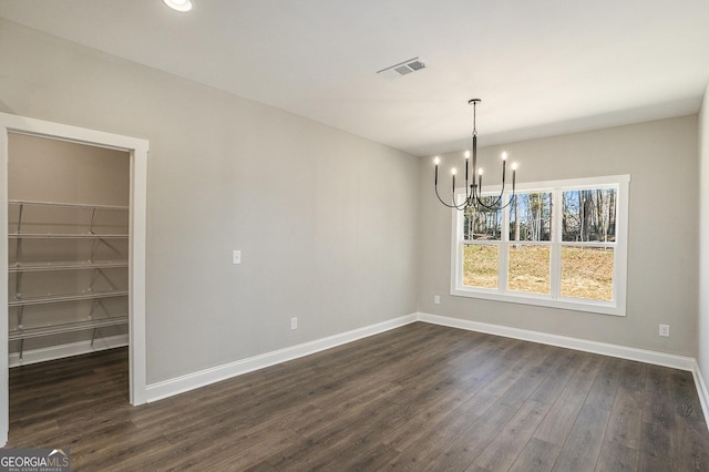 unfurnished dining area with dark wood-style flooring, visible vents, a notable chandelier, and baseboards