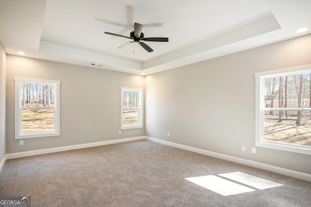 spare room with carpet, baseboards, and a tray ceiling