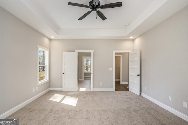 unfurnished bedroom featuring carpet floors, baseboards, and a tray ceiling