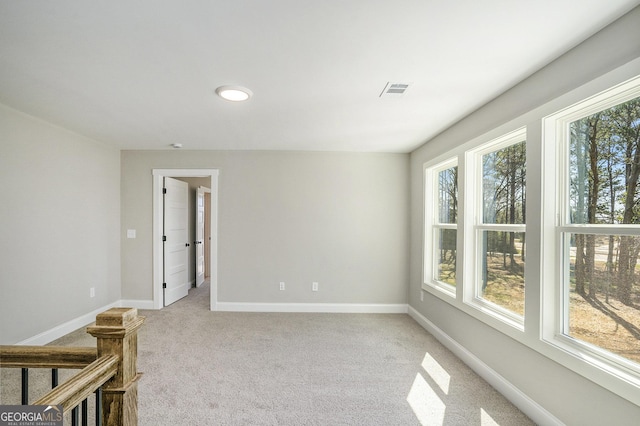 empty room with light carpet, plenty of natural light, visible vents, and baseboards