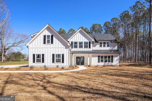 modern farmhouse featuring roof with shingles, a front lawn, and board and batten siding