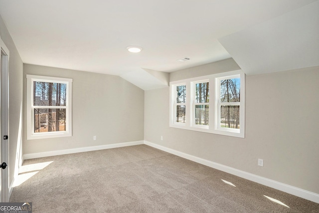 additional living space with light carpet, lofted ceiling, and baseboards