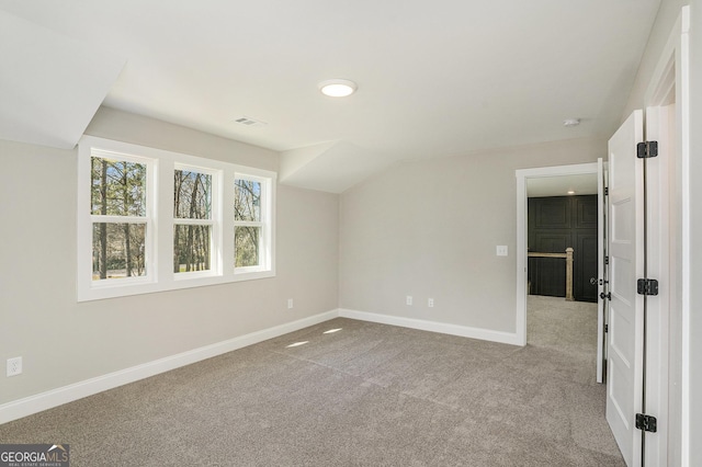 interior space featuring visible vents, baseboards, vaulted ceiling, and light colored carpet