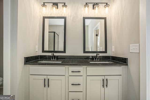 bathroom featuring double vanity, a sink, and toilet