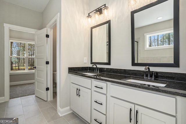 bathroom with toilet, double vanity, a sink, and tile patterned floors