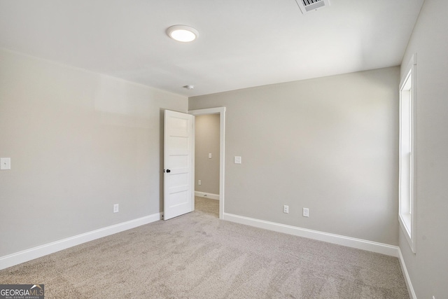 unfurnished room featuring light colored carpet, visible vents, and baseboards