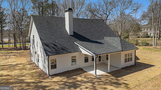 exterior space with a patio, a shingled roof, and a chimney