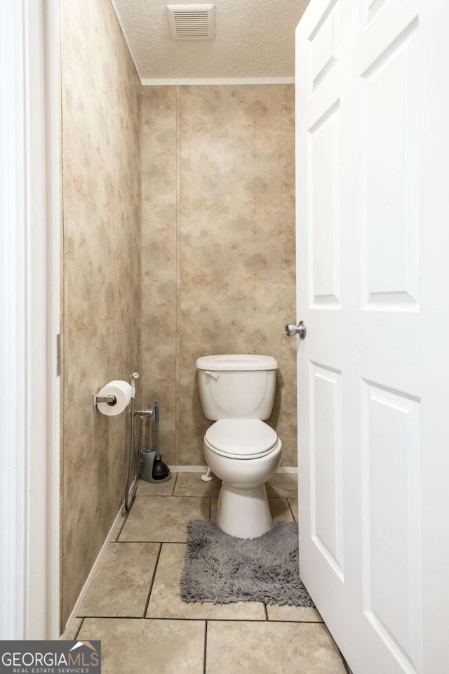 bathroom with tile patterned floors, a textured ceiling, toilet, and crown molding