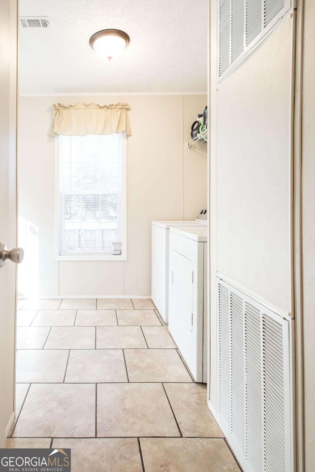 clothes washing area featuring washer and clothes dryer, light tile patterned floors, and a textured ceiling